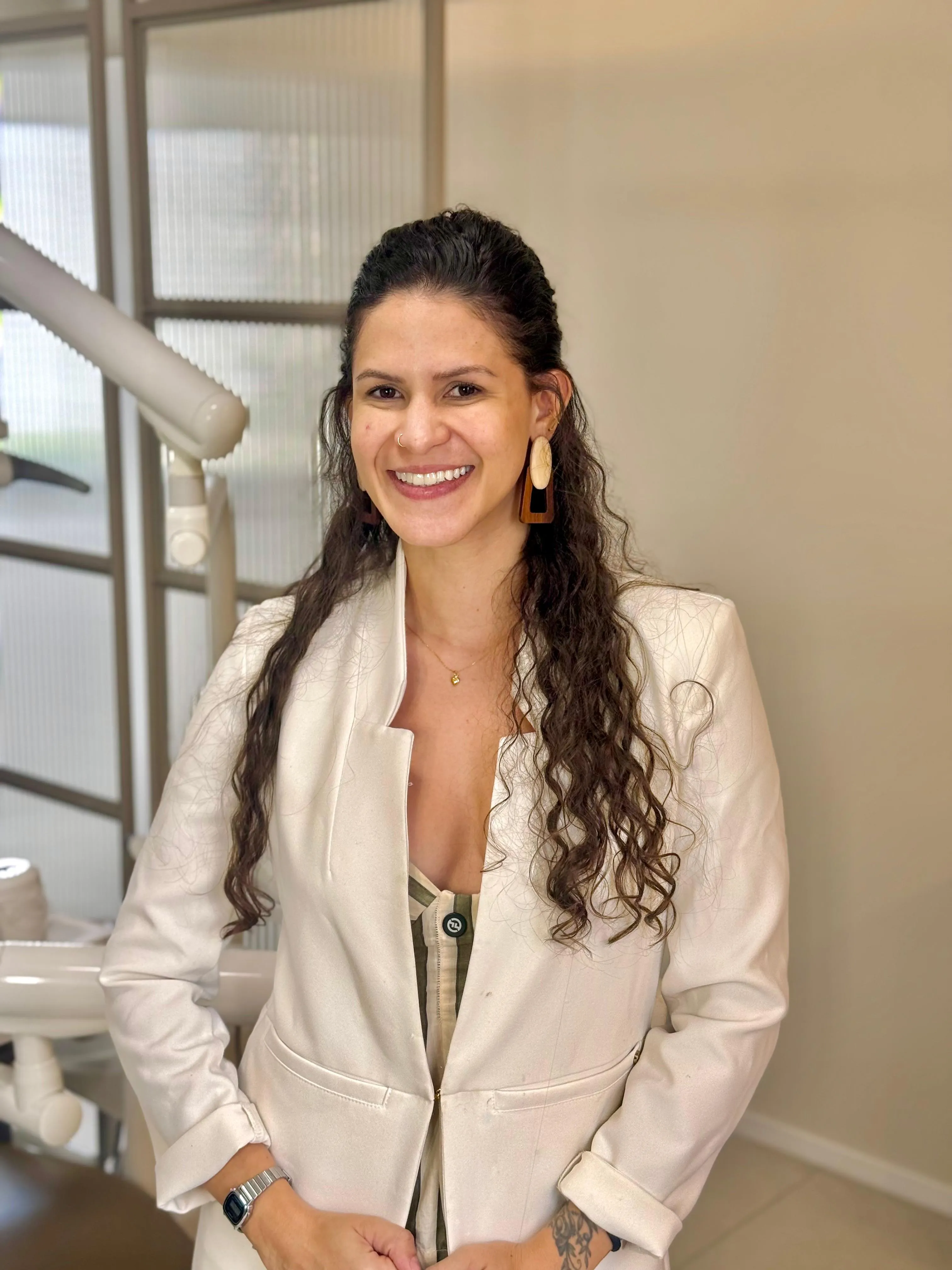 Dra. Carolina Bessa sorrindo em seu consultório